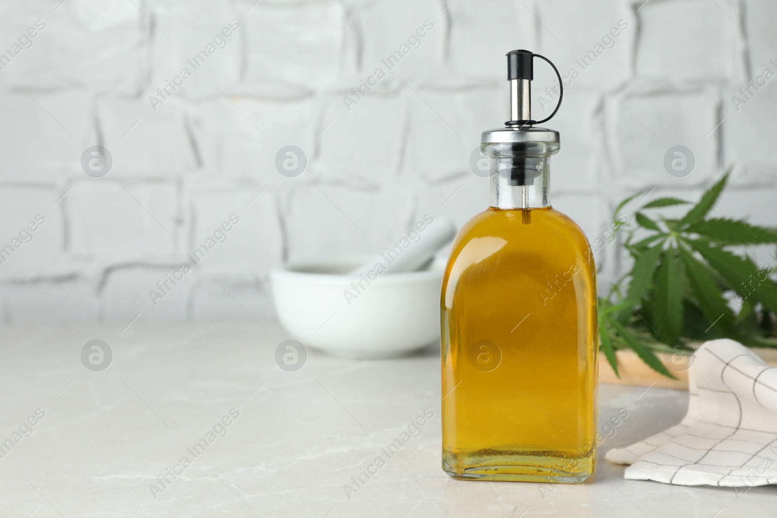 Photo of Bottle of hemp oil on light grey marble table. Space for text