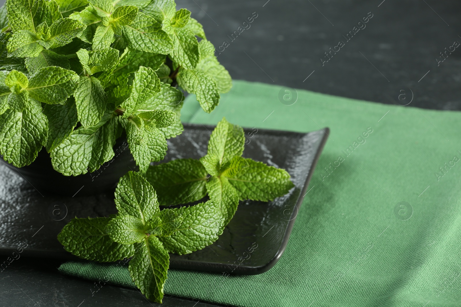 Photo of Fresh green mint leaves on black table, closeup. Space for text