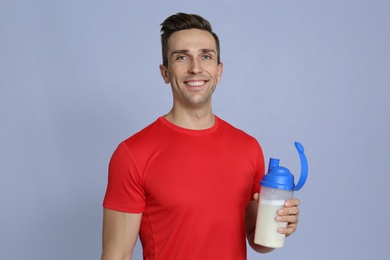 Portrait of man with bottle of protein shake on color background