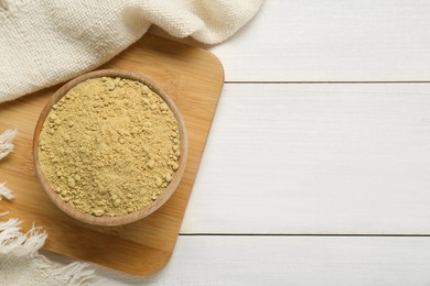 Photo of Bowl of aromatic mustard powder on white wooden table, top view. Space for text