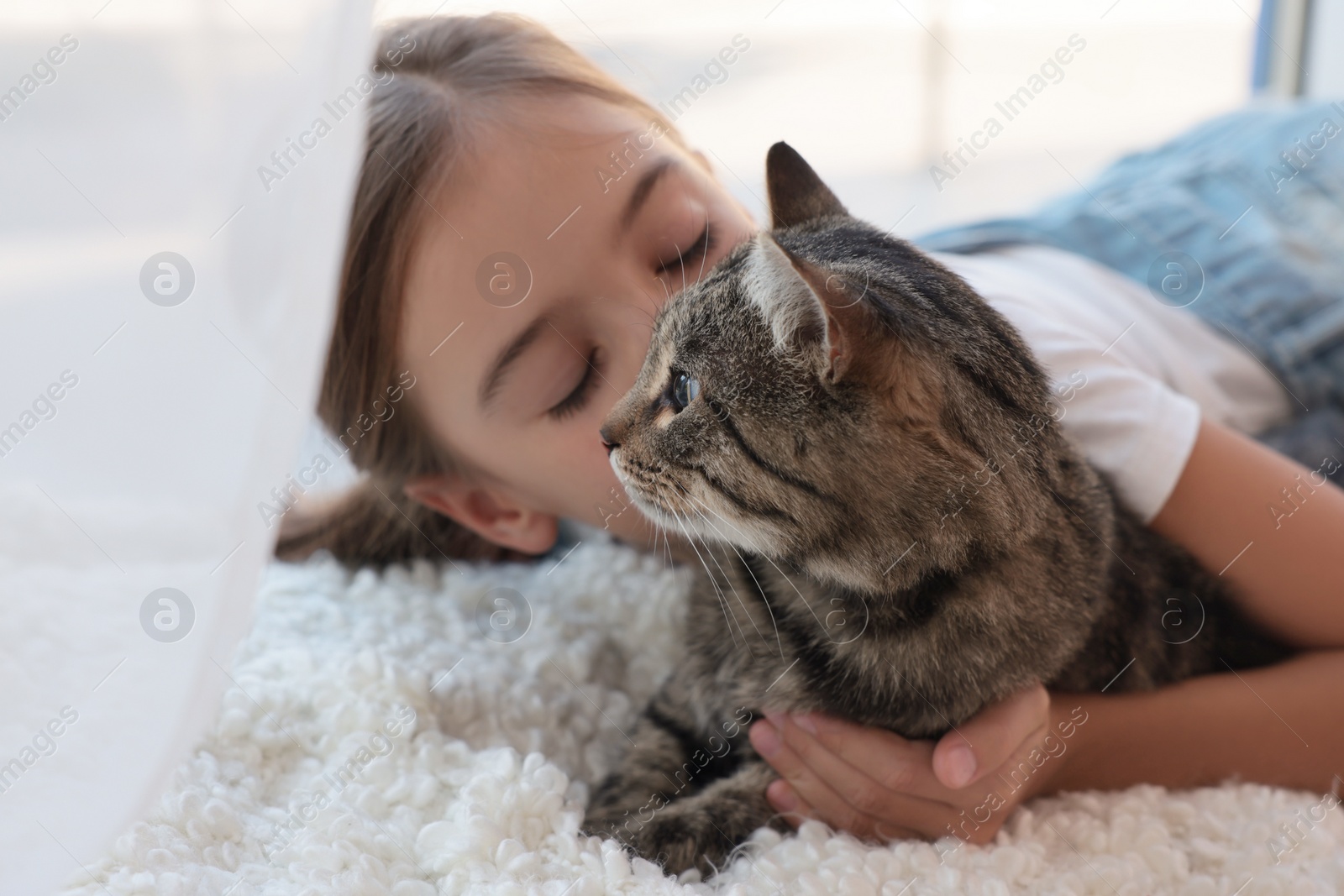 Photo of Cute little girl with her cat at home. Childhood pet