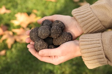 Photo of Woman holding fresh truffles in hands outdoors, closeup