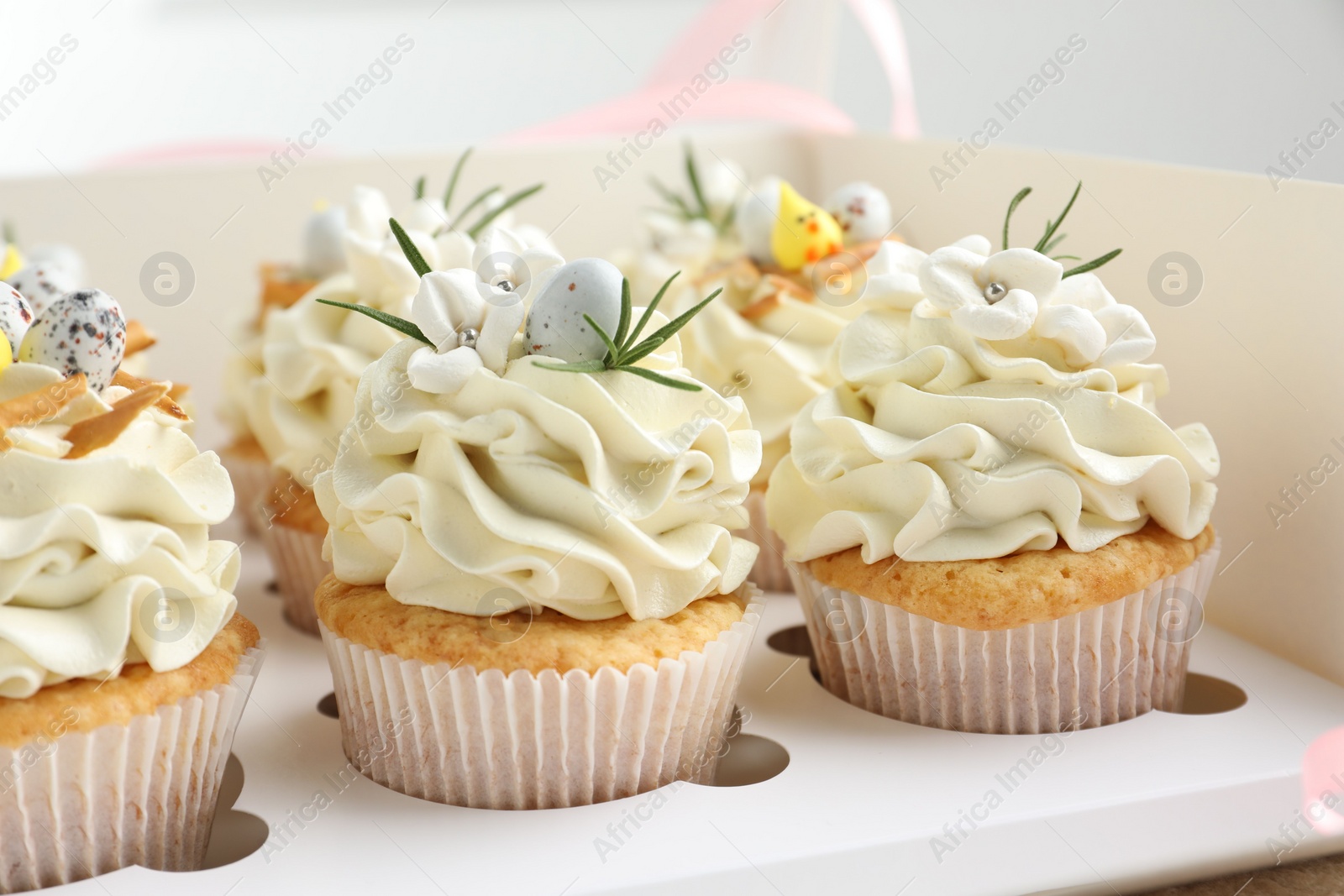 Photo of Tasty Easter cupcakes with vanilla cream in box, closeup