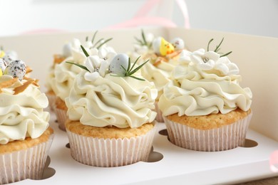 Tasty Easter cupcakes with vanilla cream in box, closeup