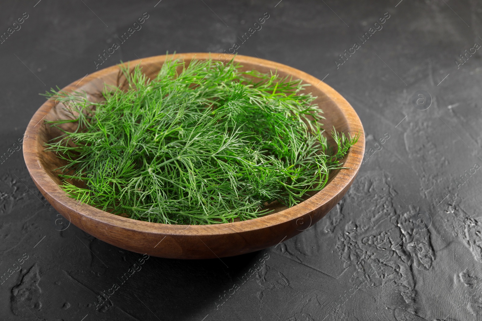 Photo of Bowl of fresh dill on grey textured table. Space for text