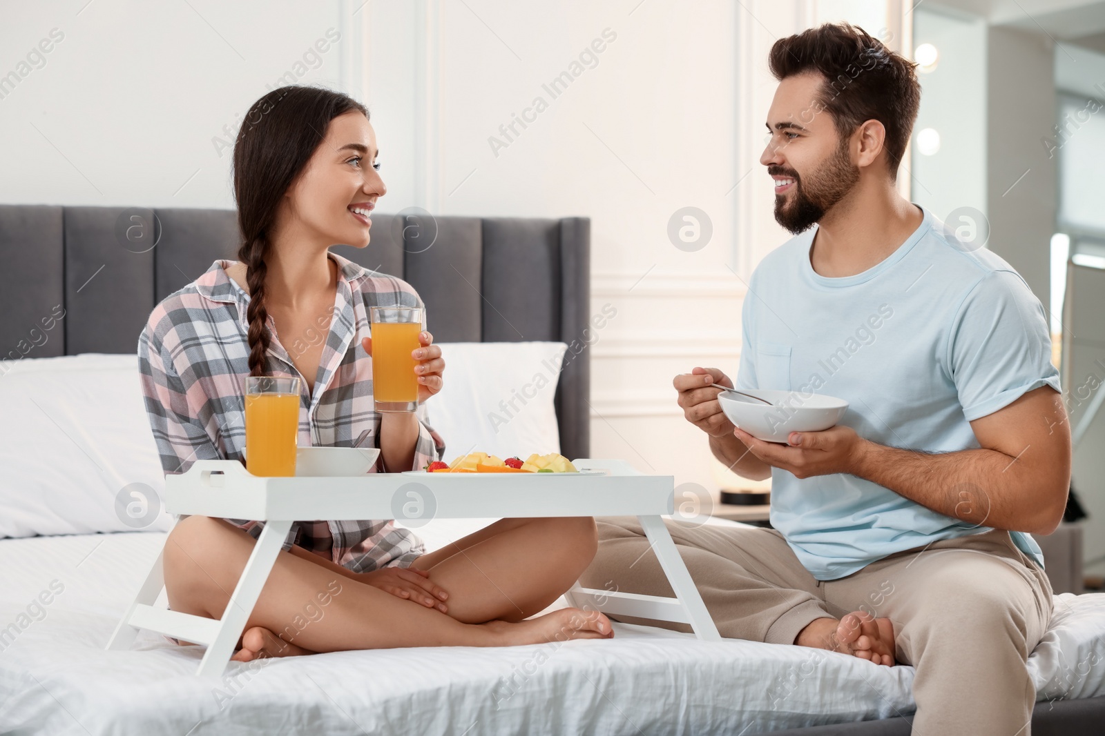 Photo of Happy couple having breakfast on bed at home