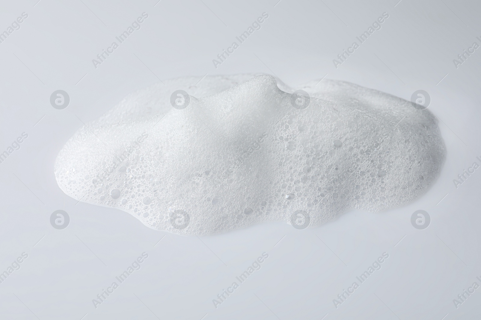 Photo of Drop of fluffy soap foam on white background