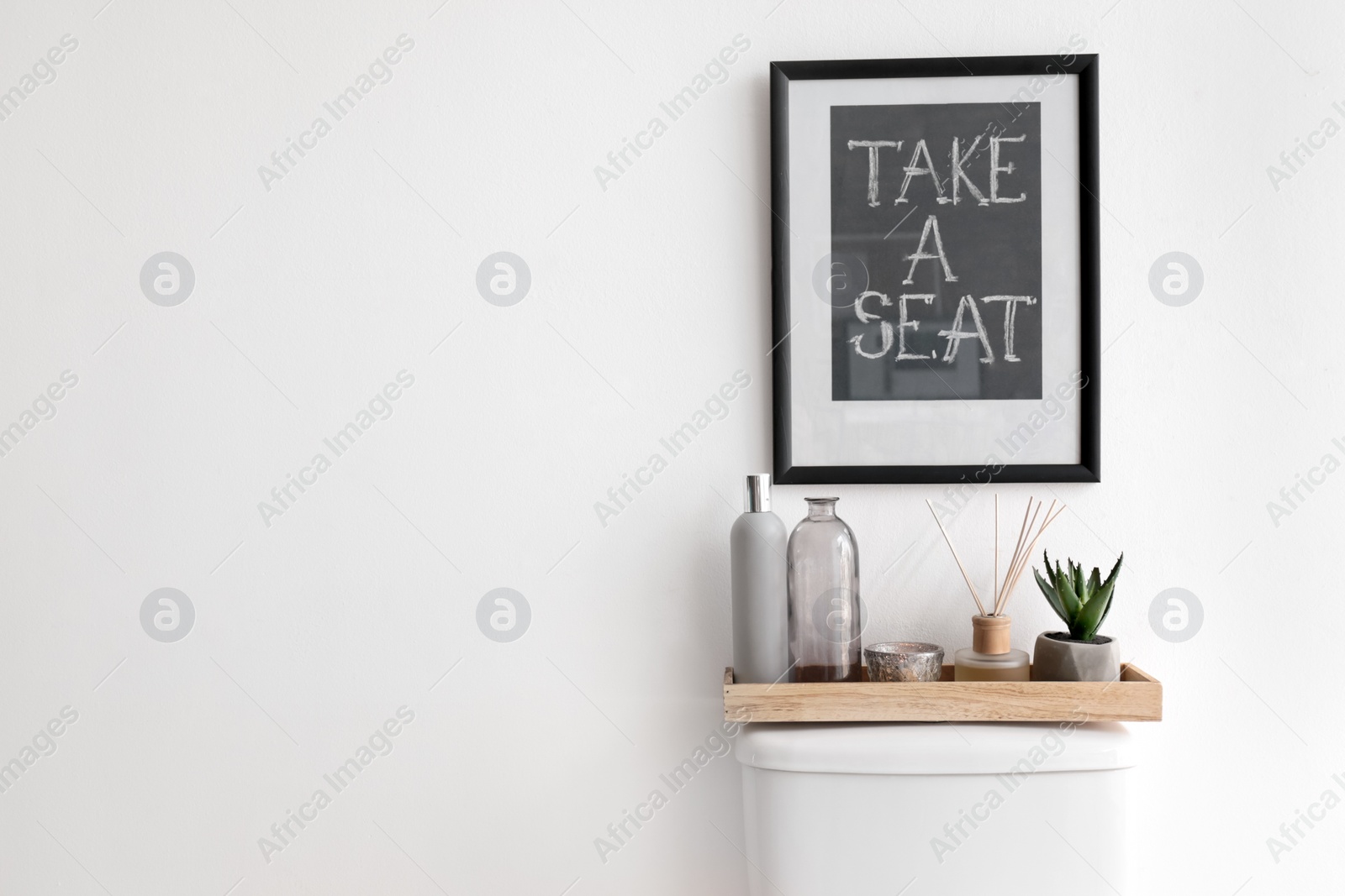 Photo of Decor elements, necessities and toilet bowl near white wall, space for text. Bathroom interior