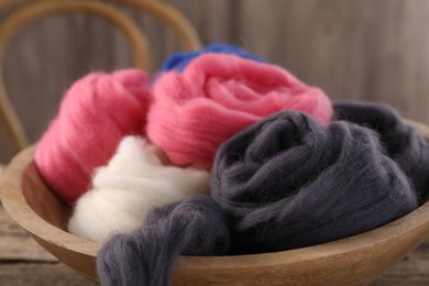 Photo of Colorful felting wool in bowl on table, closeup