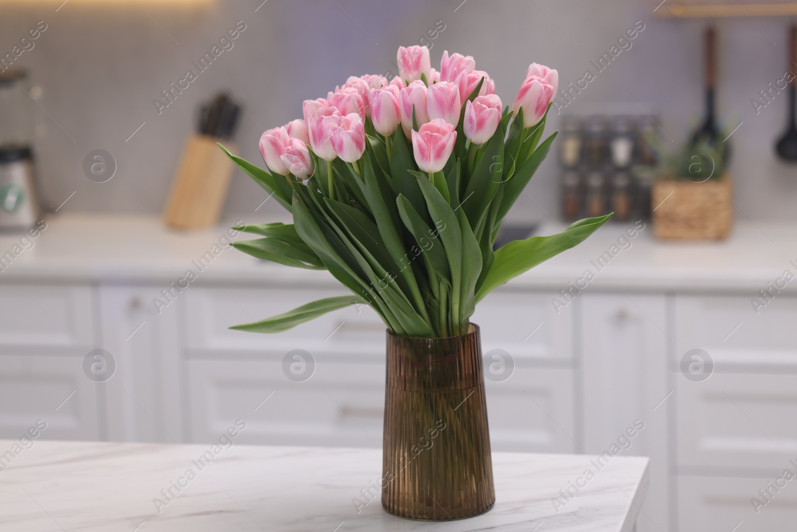 Photo of Beautiful bouquet of fresh pink tulips on table in kitchen