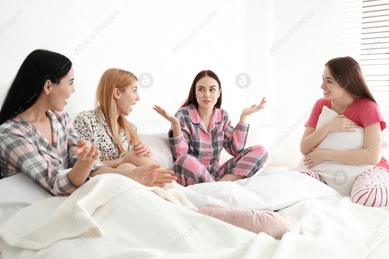 Photo of Beautiful young ladies on bed at pamper party. Women's Day