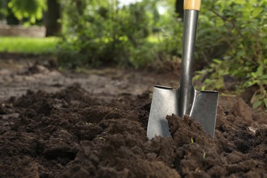 Photo of Shovel in soil outdoors, space for text. Gardening tool