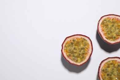 Halves of passion fruits (maracuyas) on white background, flat lay. Space for text