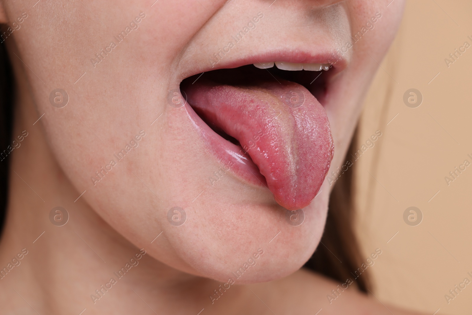 Photo of Woman showing her tongue on beige background, closeup