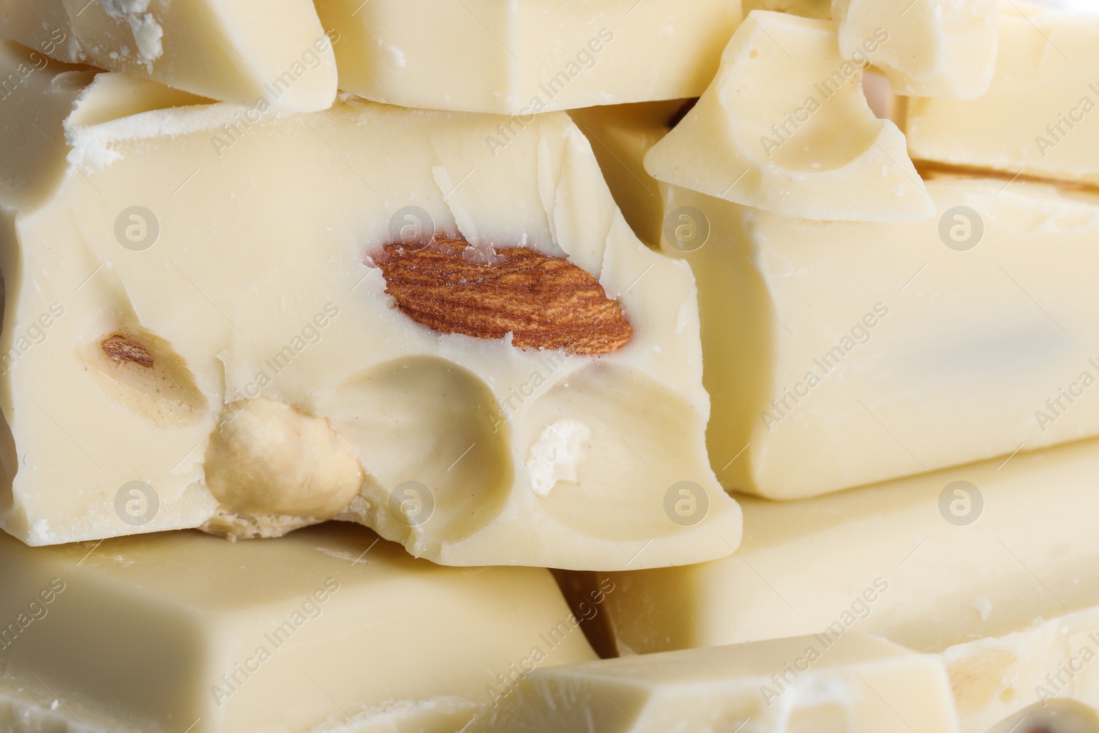 Photo of Pieces of white chocolate with nuts as background, closeup