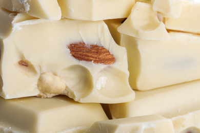 Photo of Pieces of white chocolate with nuts as background, closeup