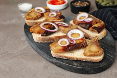 Photo of Tasty fried pork lard with bread slices and onion on grey table