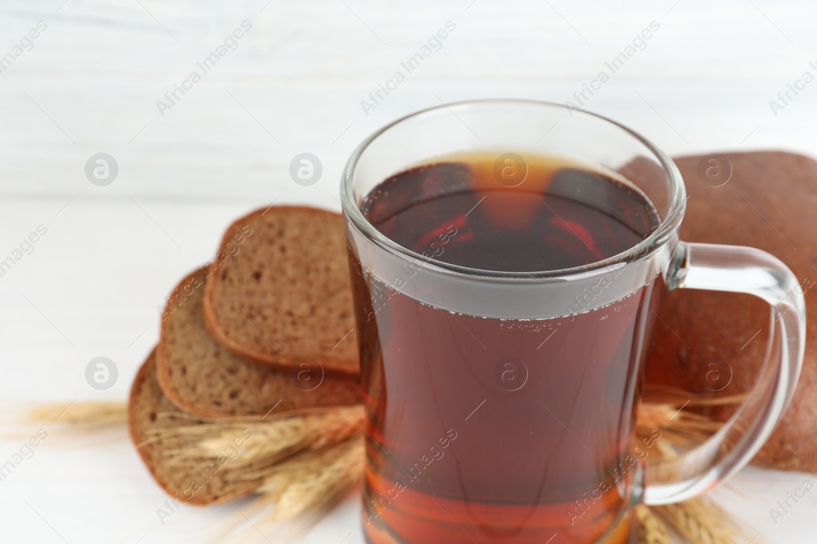 Photo of Mug of delicious kvass on white table, closeup