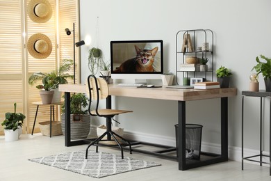 Photo of Comfortable workplace with computer in light room. Interior design