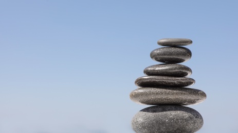 Photo of Stack of stones against blue sky, space for text. Zen concept