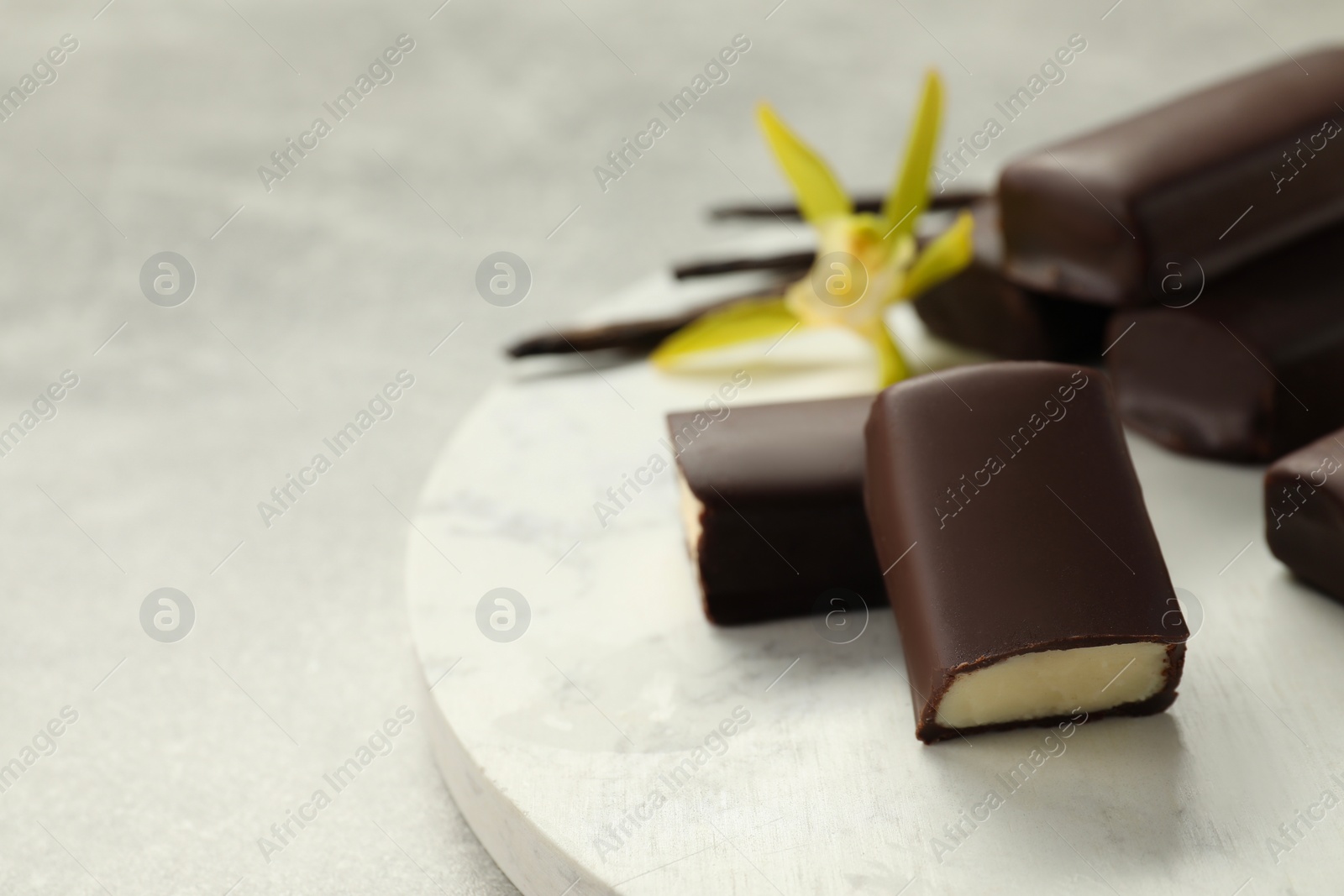 Photo of Glazed curd cheese bars, vanilla pods and flower on grey table, closeup. Space for text