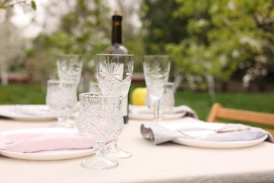 Stylish table setting with beautiful spring flowers, wine, plates and glasses in garden