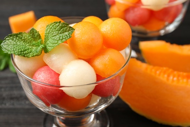 Photo of Melon and watermelon balls with mint in dessert bowl on table, closeup