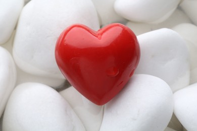 Red decorative heart on stones and water, top view