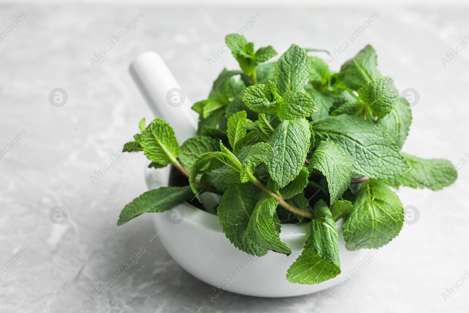 Photo of Mortar with fresh green mint and pestle on table