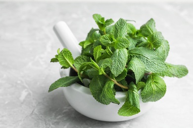 Mortar with fresh green mint and pestle on table