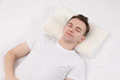 Photo of Man sleeping on orthopedic pillow in bed