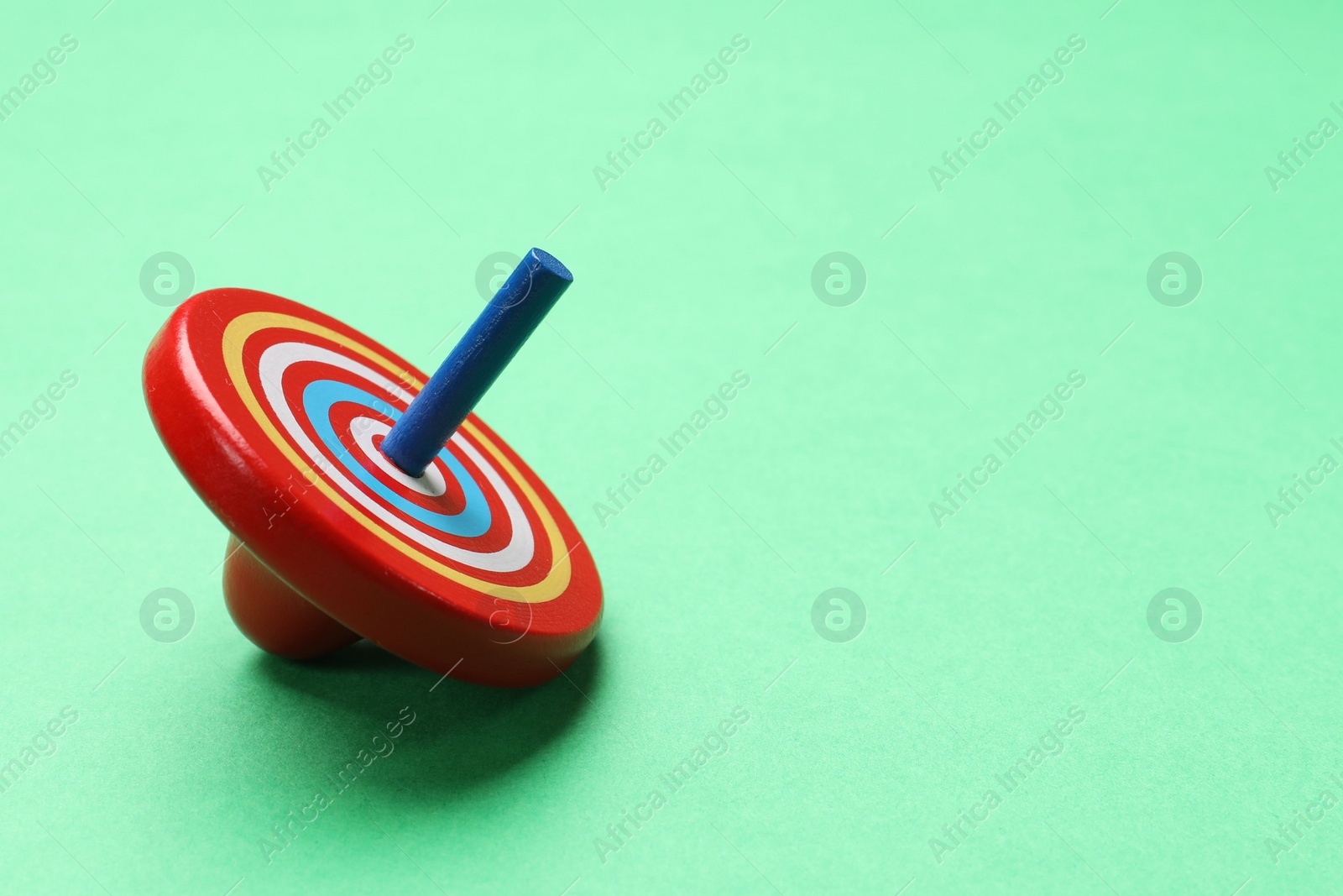 Photo of One bright spinning top on aquamarine background, space for text