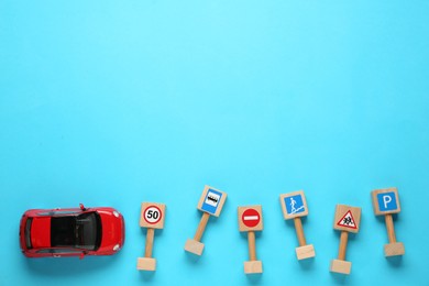 Photo of Many different miniature road signs and car on light blue background, flat lay with space for text. Driving school