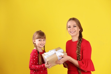 Photo of Happy mother and daughter with gift on color background. International Women's Day