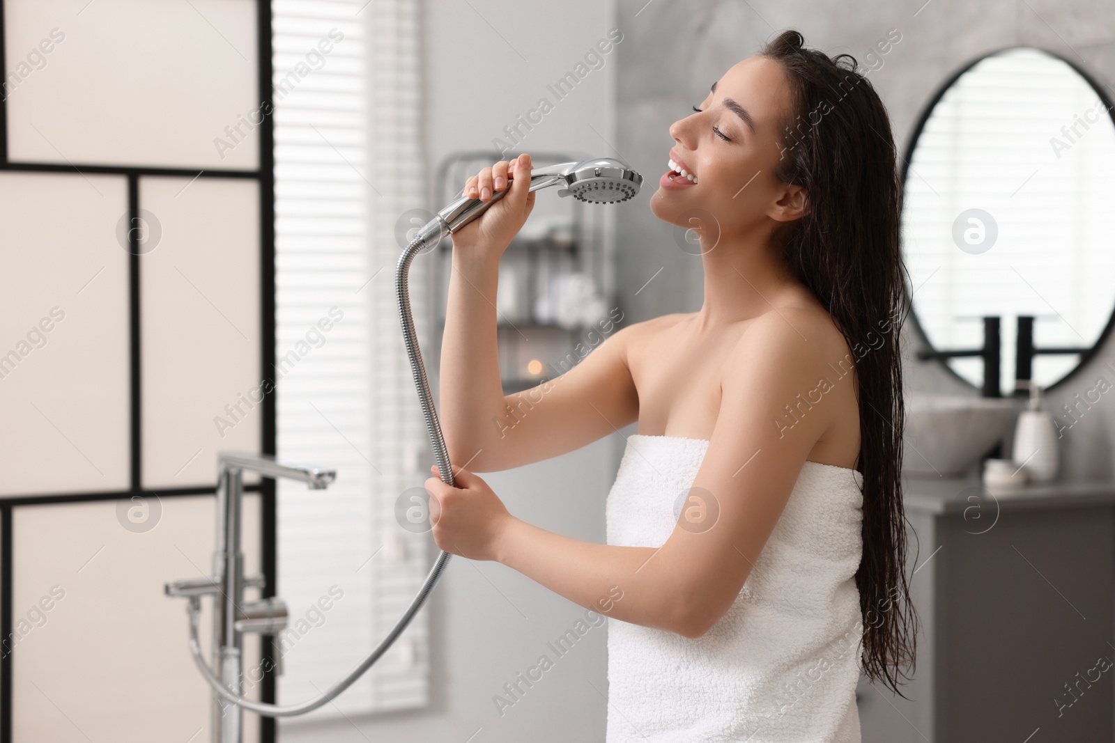 Photo of Happy woman singing after shower in bathroom
