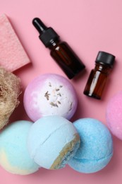 Bath bombs, loofah sponge, soap bar and bottles on pink background, flat lay