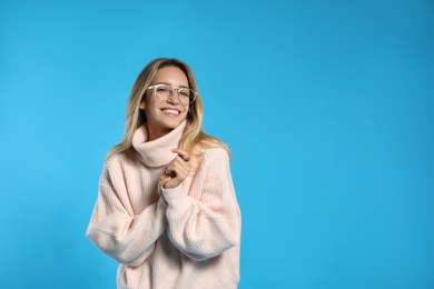 Photo of Beautiful young woman wearing knitted sweater on light blue background. Space for text