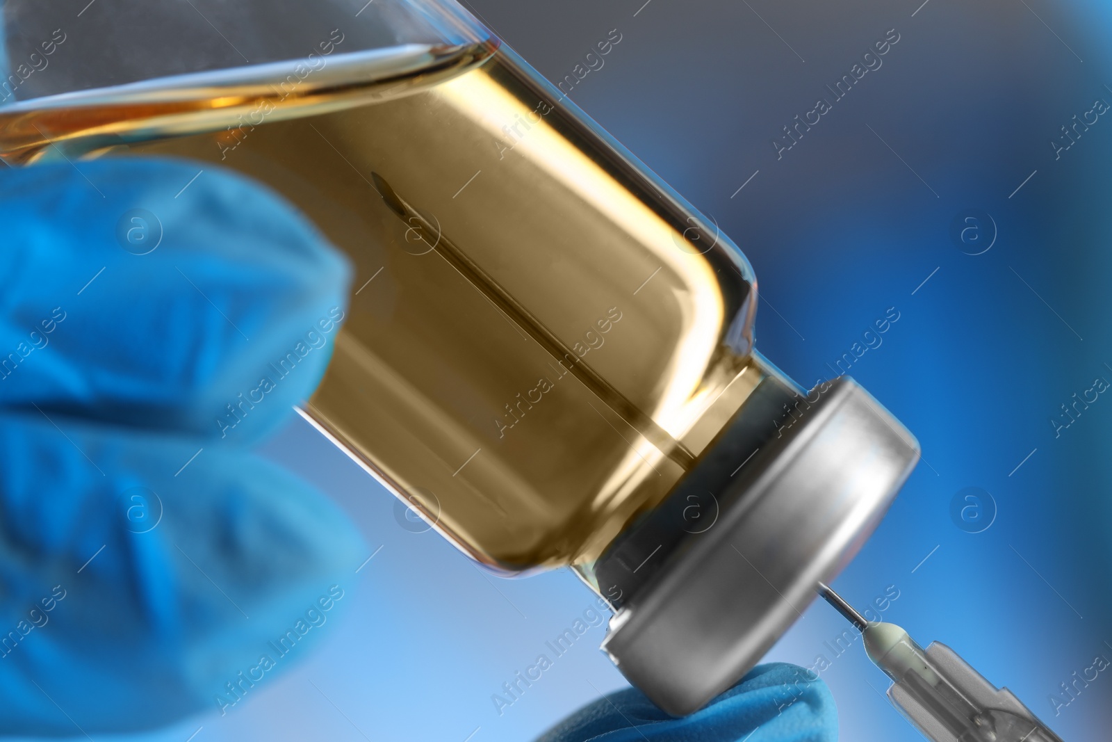 Photo of Doctor filling syringe with medication from glass vial, closeup