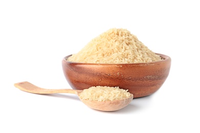 Photo of Bowl and spoon with uncooked parboiled rice on white background