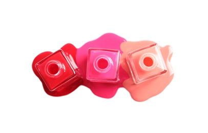 Photo of Spilled different nail polishes with bottles on white background, top view