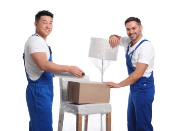 Workers wrapping box in stretch film on white background