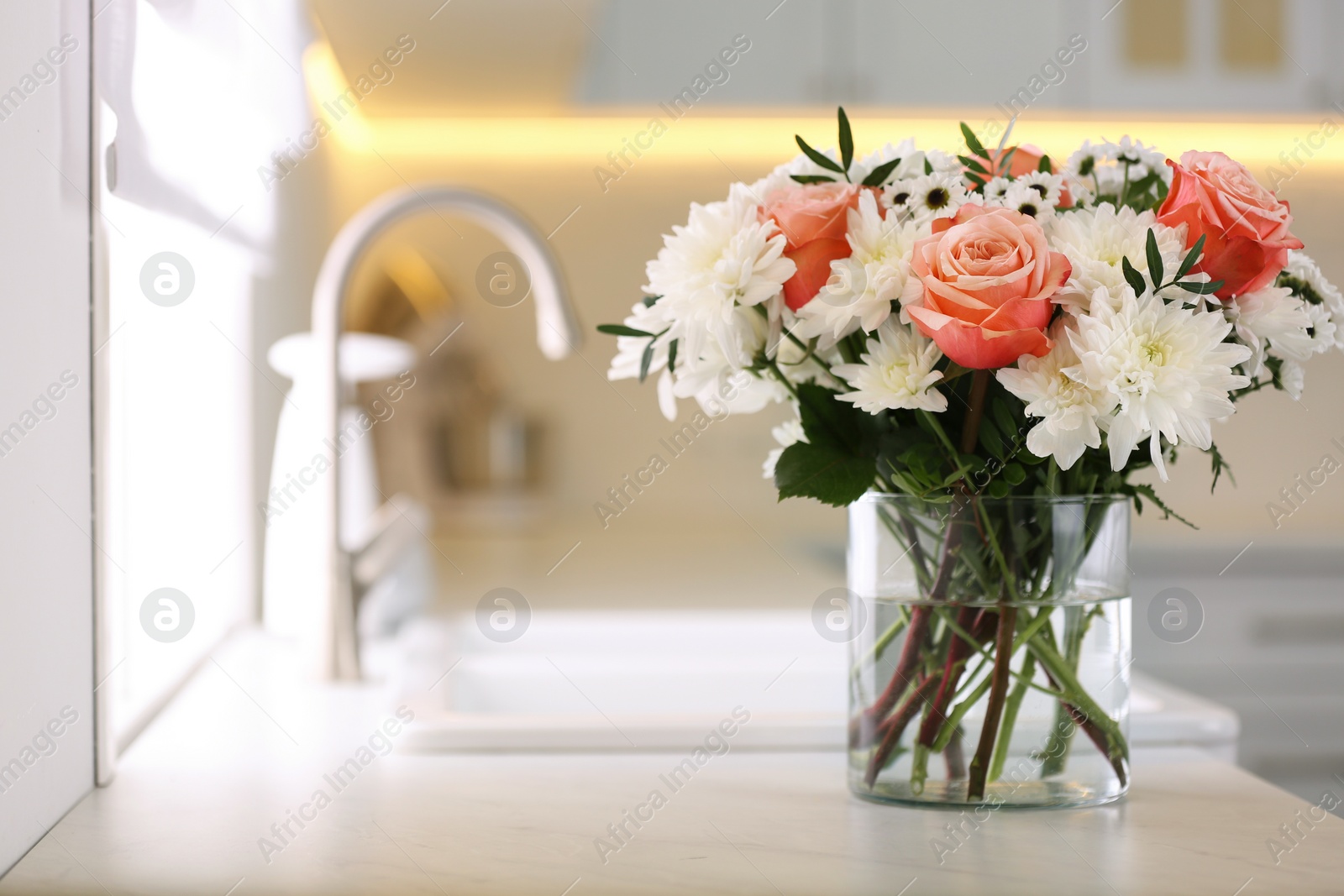 Photo of Vase with beautiful flowers on countertop in kitchen, space for text. Interior design