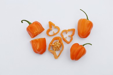 Photo of Whole and cut orange hot chili peppers on white background, flat lay