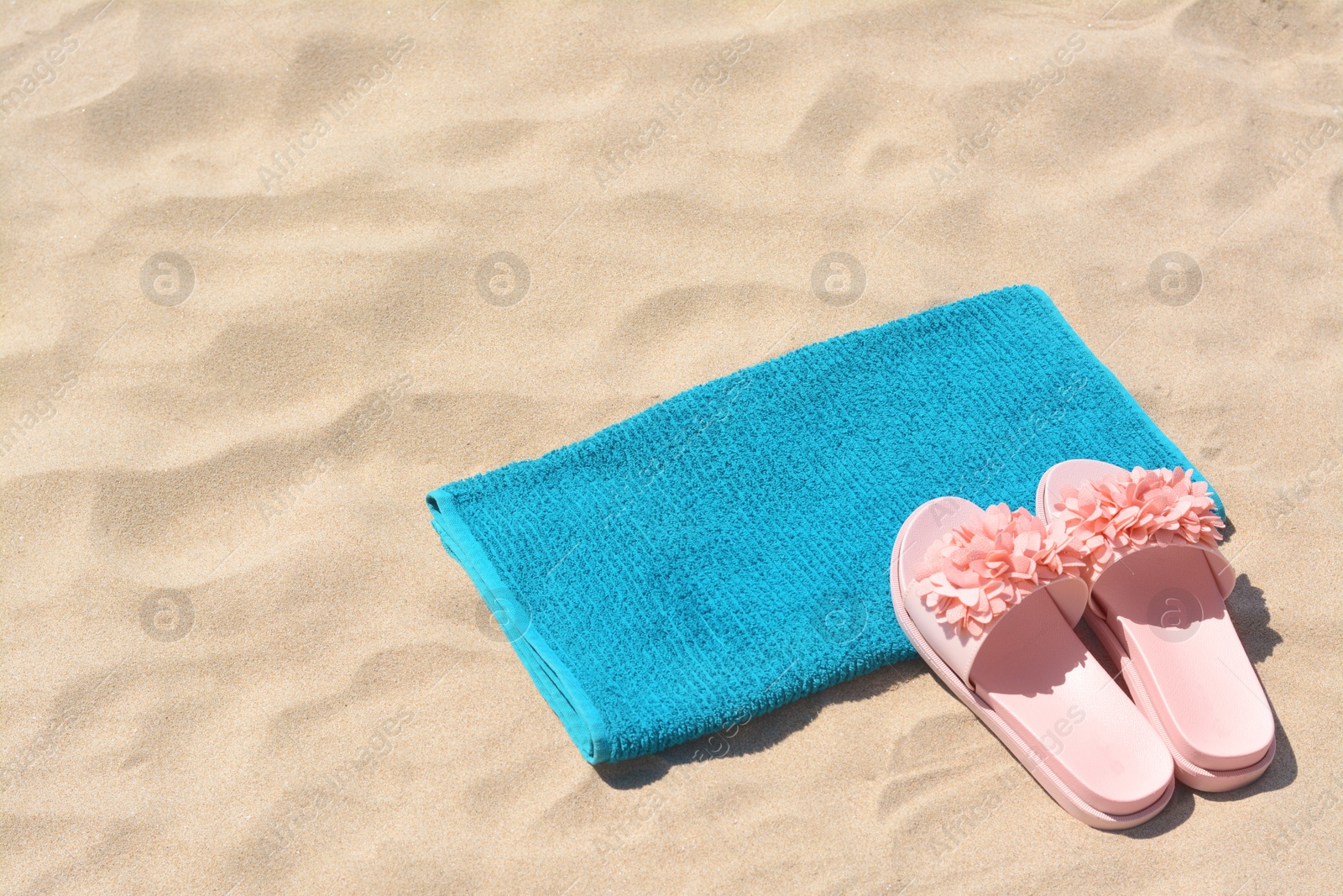 Photo of Towel and stylish slippers on sand, space for text. Beach accessories