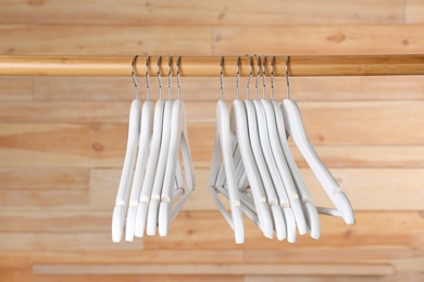 Rack with clothes hangers on wooden background