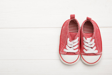 Photo of Top view of child's booties on white wooden background, space for text