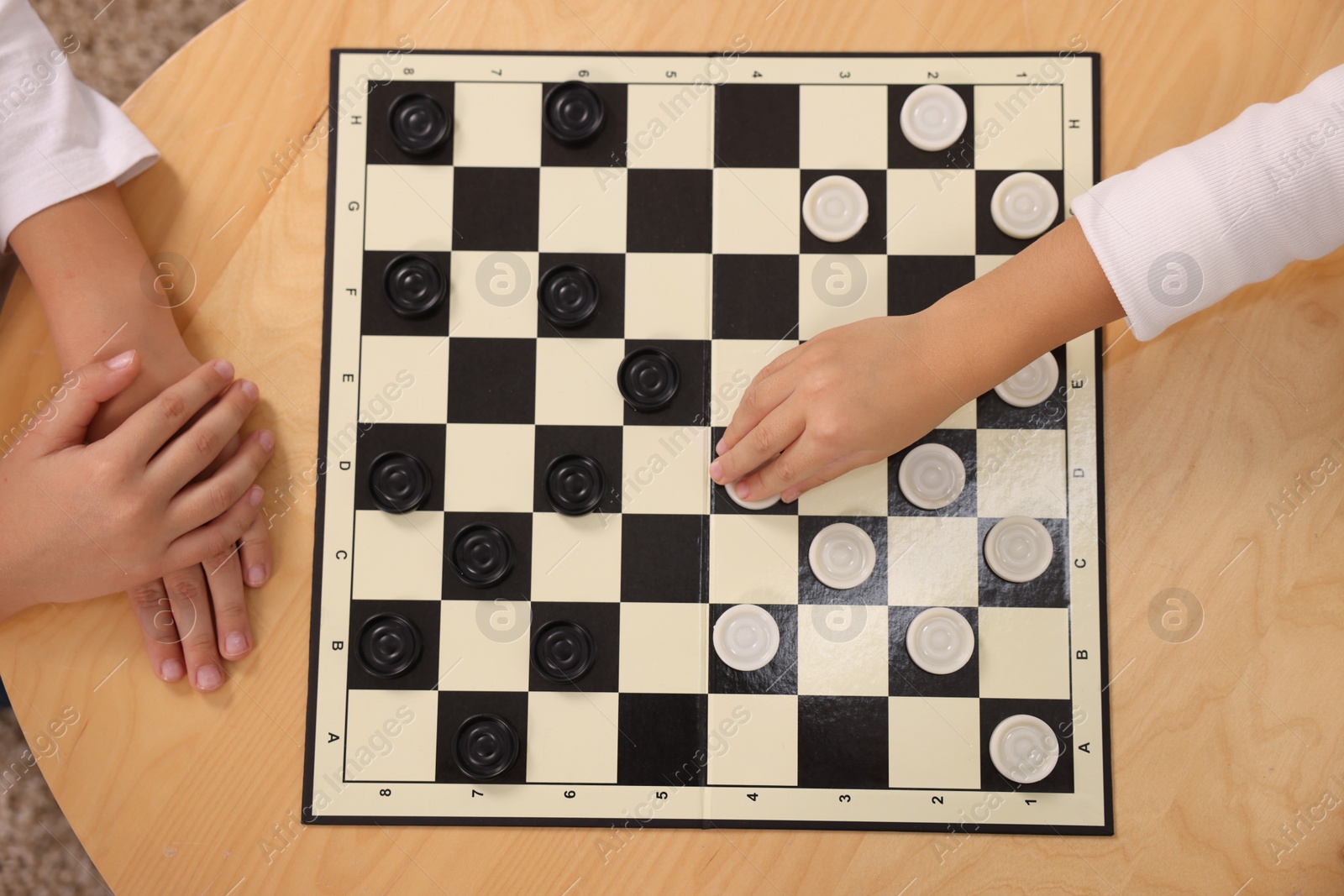 Photo of Children playing checkers at coffee table, top view