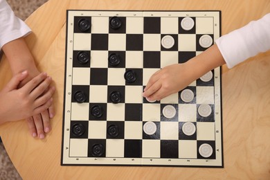 Photo of Children playing checkers at coffee table, top view