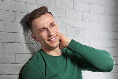 Portrait of young man with beautiful hair on brick wall background