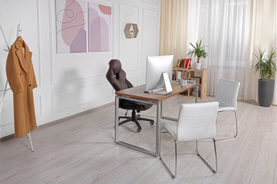 Photo of Director's workplace with wooden table, computer and comfortable armchairs. Interior design